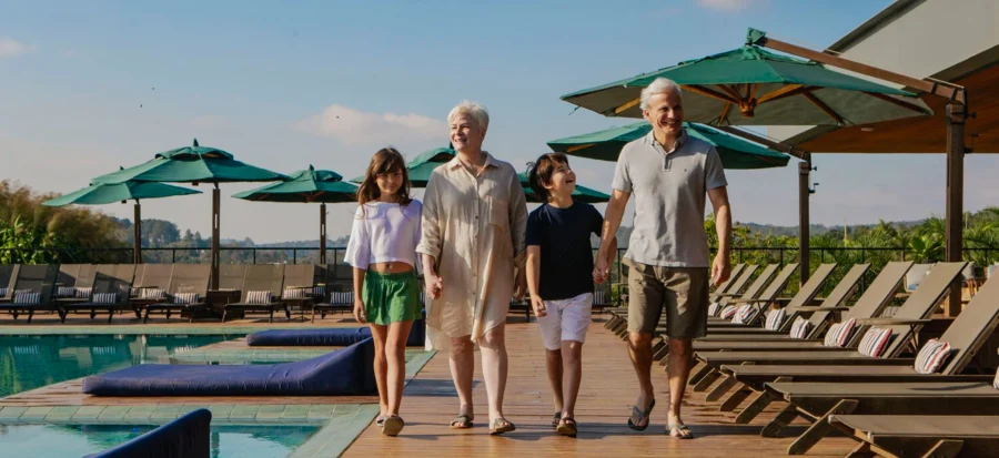 casal de idosos passeando com os netos perto da piscina do clara resorts