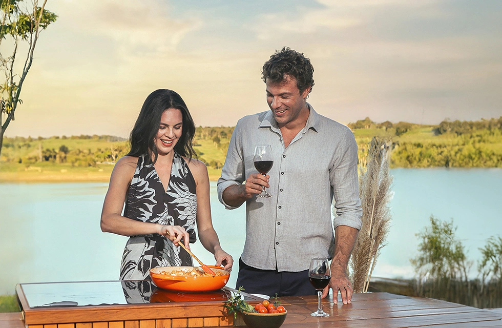 casal cozinhando a beira da represa do resort