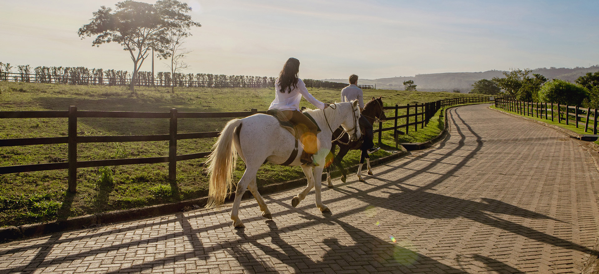 duas pessoas andando a cavalo no resort, aproveitando a paisagem e o momento de férias