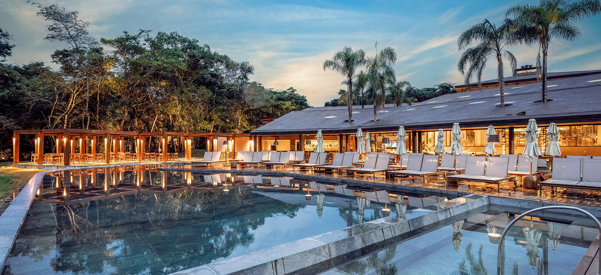 vista da piscina externa adulto e infantil, bem equipada com cadeiras e espaço para as pessoas se divertirem no resort