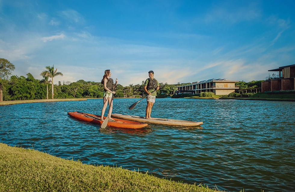 Casal se divertindo fazendo stand-up paddle no lago do Clara Dourado