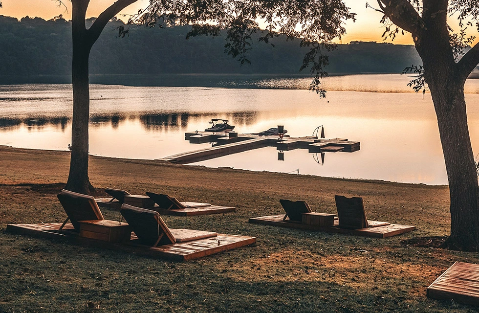 local aconchegante no lago com cadeiras de chão e vista limpa para o horizonte; espaço de extensão do resort para conectar o hóspede à natureza